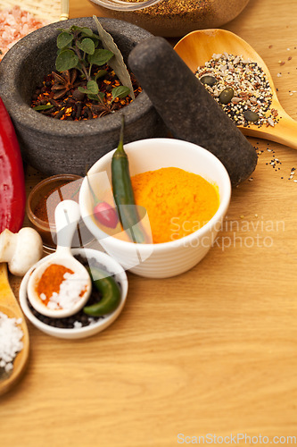 Image of Table top, mortar and food spices for cooking gourmet meal, turmeric seasoning or flavor pestle. Pepper vegetables, kitchen condiments and variety of plant herbs for brunch, healthy diet or vitamins.