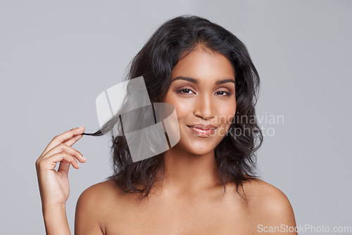 Image of Portrait, beauty and hair with a woman in studio on a gray background for natural hair treatment. Face, skin care and shampoo with a young Indian female model at the salon for a haircut or cosmetics