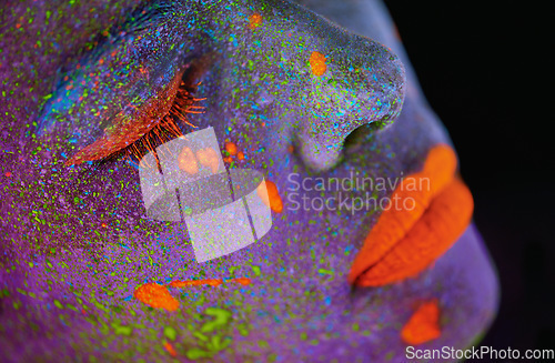 Image of Neon paint, beauty and woman face closeup with dark background and creative cosmetics. Glow makeup, fantasy and psychedelic cosmetic of a female model with unique and creativity with art in studio