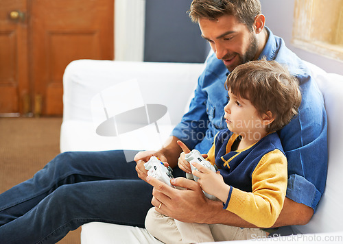 Image of Gaming, dad and son on a sofa, playful and bonding with fun, happiness and chilling at home. Family, father and boy with parent, male child and kid with controller, video games and multi player app