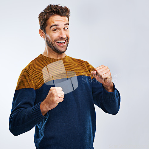 Image of Portrait, winner and man with energy, fist and excitement with guy isolated against a studio background. Face, male person and model winning, goals and happiness with victory, wow and omg with joy