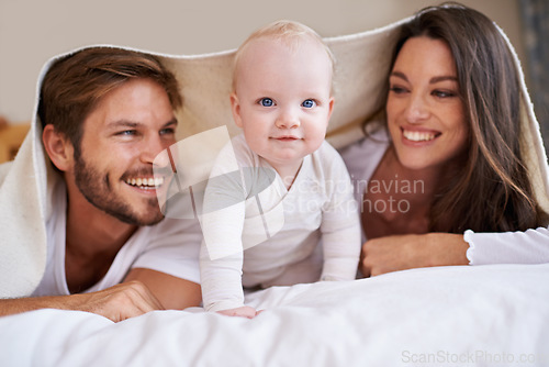 Image of Portrait of baby, happy mother and father with blanket in bedroom for love, care and quality time together. Fun parents, playful newborn child and family relaxing with bedding fort, smile and at home
