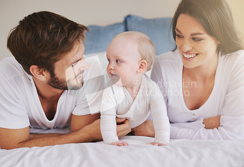 Image of Happy family, mother and father with baby on bed for love, care and quality time together at home. Mom, dad and cute newborn child relaxing in bedroom for happiness, support and development of kids