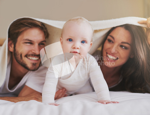 Image of Mother, father and baby under blanket on bed for love, care and quality time together. Portrait of playful child, happy family and kids relaxing in bedroom with bedding fort, fun and bonding in house