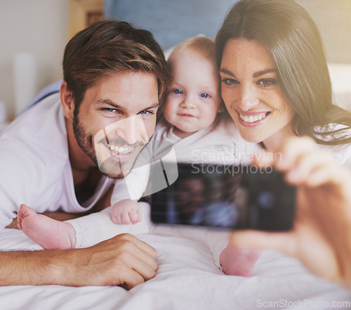 Image of Happy family, parents and selfie of baby on bed in home for love, care and quality time together. Mother, father and newborn child smile for photograph, fun memory and happiness of bonding in bedroom