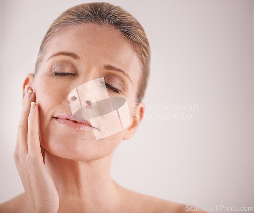 Image of Face, beauty and mockup with a mature woman in studio on a mockup background for natural antiaging treatment. Facial, skincare and wellness with an attractive elderly female model touching her cheek