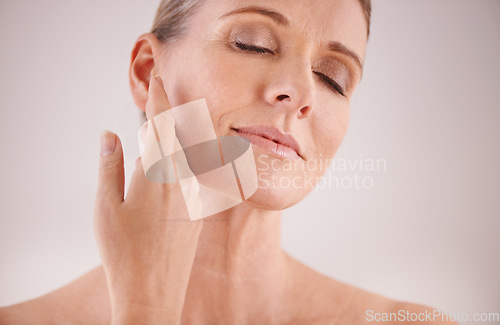 Image of Face, beauty and skincare with an old woman in studio on a gray background for natural antiaging treatment. Facial, skin care and wellness with an attractive senior female model touching her cheek