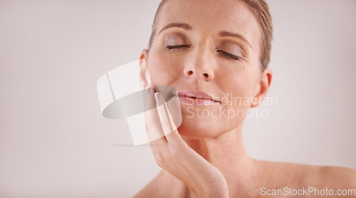 Image of Face, beauty and mockup with a mature woman in studio on a gray background for natural antiaging treatment. Facial, skincare and wellness with an attractive senior female model touching her cheek