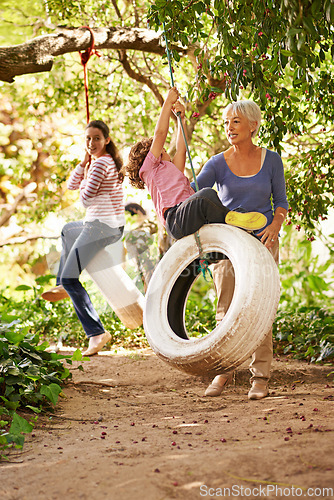 Image of Grandmother, garden and grandkids playing with senior woman on tyre swing or holiday and having fun in summer. Excited, grandchildren and outdoors on jungle gym together or on sunny weekend at a park