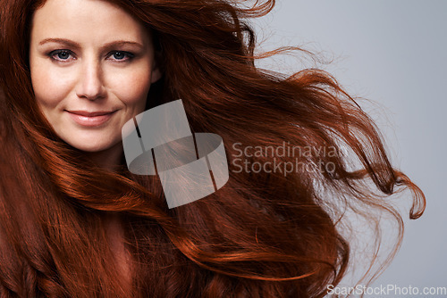 Image of Redhead, wind and hair portrait of woman in studio for treatment, wellness and beauty on gray background. Salon, hairdresser and happy face of female model with shine, healthy and natural hairstyle