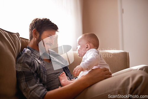 Image of Smile, father and baby sitting on lap on sofa in home living room, bonding or playing together. Happiness, care and dad with newborn child on couch in lounge, having fun and enjoying relax time.