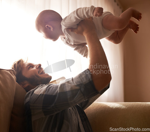 Image of Funny, father and lifting baby on sofa in home living room, playing or bonding together. Happy, care and dad holding infant, newborn or child on couch in lounge, having fun and enjoying quality time.