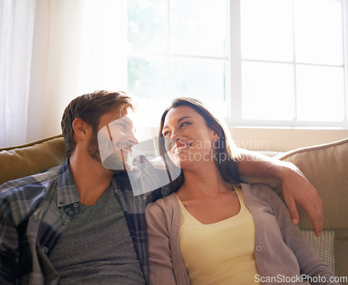 Image of Couple, love and hug or smile at each other on a couch or in the living room and conversation. Man, woman and relationship or bonding and happy partners affectionate or at home relaxing and embrace