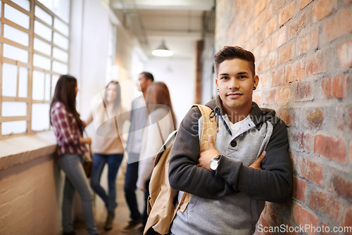 Image of Education, arms crossed and portrait of man in college hallway for studying, learning or scholarship. Future, school and knowledge with student leaning on brick wall for university, academy or campus