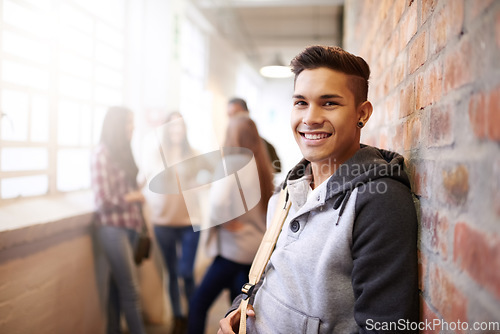 Image of Education, smile and portrait of man in college hallway for studying, learning and scholarship. Future, happy and knowledge with student relax on brick wall for university, academy and campus