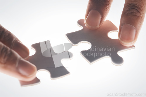 Image of Hands, puzzle and strategy in closeup for problem solving, mindset or connection with glow by white background. Games, jigsaw and link for innovation, synergy and solution with people, team or help