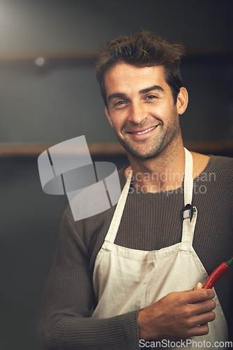 Image of Chef, hot pepper and portrait of man in kitchen with vegetables for vegetarian, healthy diet or vegan ingredients. Smile, male cook holding chilli and food for spices from Norway for cooking in home