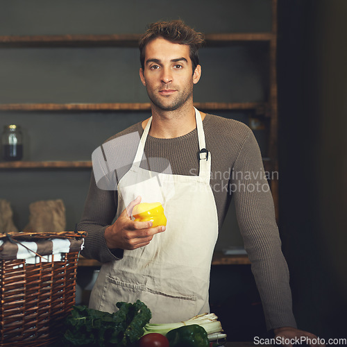 Image of Chef, pepper and portrait of man in kitchen with vegetables for serious vegetarian, healthy diet or vegan ingredients. Cooking, male cook holding capsicum and food from Canada in rustic restaurant