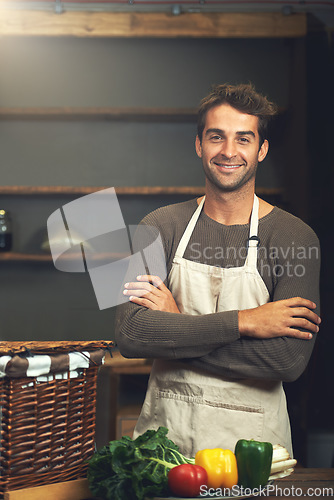 Image of Chef, smile and portrait of man with arms crossed in rustic kitchen with vegetables for nutrition and vegan ingredients. Confidence, male cook and happy person from Norway ready to start cooking.
