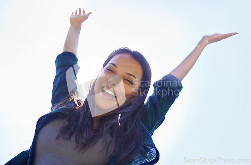 Image of Portrait, celebrate life and arms with a woman outdoor in nature for fun, freedom or adventure in summer from below. Smile, clear sky and wellness with a happy young person outside during the day