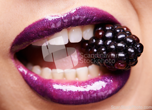 Image of Woman lips closeup, purple lipstick with blackberry and makeup, shine and creativity with beauty. Fruit between female model teeth, cosmetics product and cosmetology, mouth with shiny lip gloss