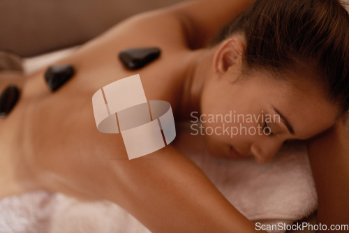 Image of Back, hot stone massage and woman in bed with luxury service for muscle, body and relax with peace in resort. Girl, hospitality and physical therapy for spine with wellness, spa and natural healing