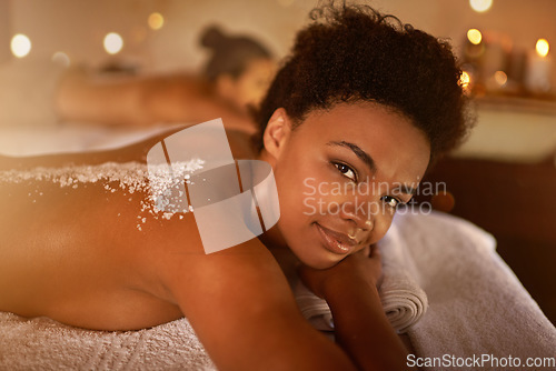 Image of Salt, spa application and black woman portrait of customer at a hotel with lying for massage. Exfoliate therapy, luxury and relax treatment of a female person back for skincare and wellness