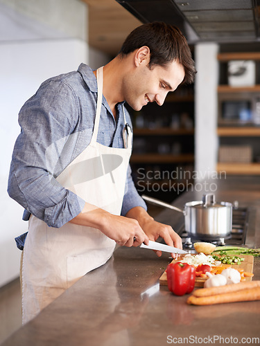 Image of Cooking, man and smile in a kitchen with food, vegetables and ingredients for meal. Happy, male person and healthy diet in house for nutrition eating and chef learning with wellness from chopping