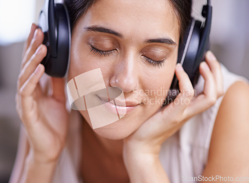 Image of Calm woman, headphones and listening to music with smile on sofa for free time, comfort or relaxing at home. Female face smiling on living room couch with headset for audio sound track or relaxation