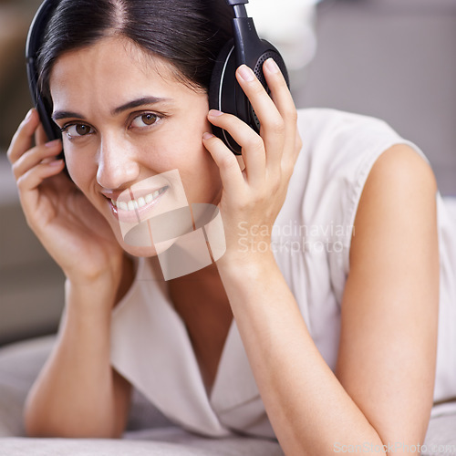 Image of Happy woman, face and headphones listening to music with smile on sofa for free time, comfort or relaxing at home. Portrait of female smiling on living room couch with headset for audio sound track