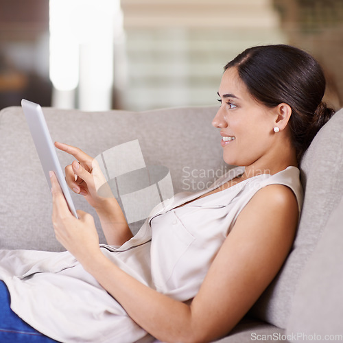 Image of Happy woman, tablet and relax on living room sofa for streaming, browsing or social media at home. Female relaxing on technology for online entertainment, app or research lying on lounge couch