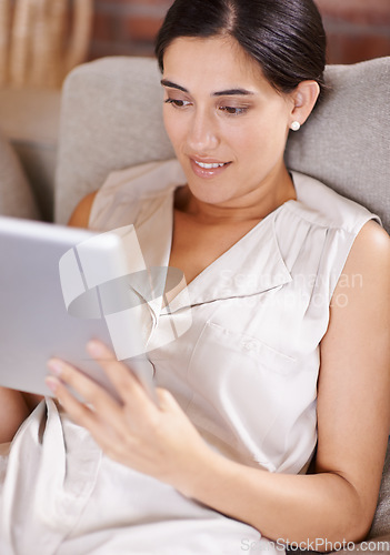 Image of Happy woman, tablet and browsing on living room sofa for streaming or social media at home. Female relaxing with smile using technology for online entertainment, app or research lying on lounge couch
