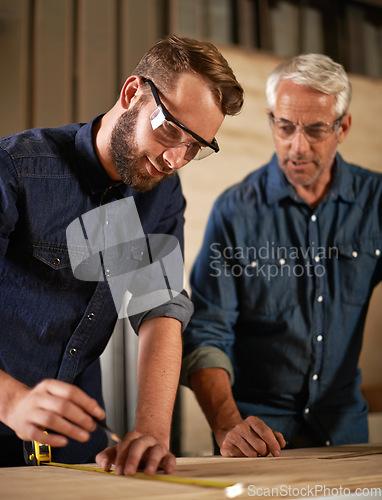 Image of Wood, learning and carpentry apprentice with mentor in designer furniture manufacturing workshop. Mentorship, senior carpenter and young man, measuring tape and focus on teaching sustainable business