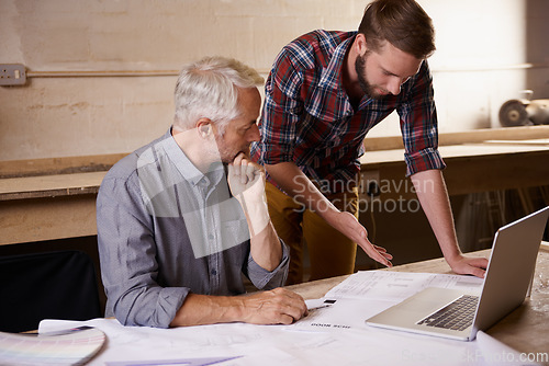 Image of Architecture, collaboration and father and son with blueprint in workshop for building construction on laptop. Senior engineer, men and paperwork of trainee or apprentice working on design and plan.