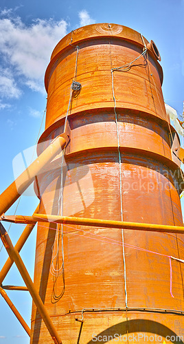 Image of A tall silo water tower against a blue sky background from below. An orange storage tank for the farming or agriculture industry used for large scale grain or wheat production on a farm