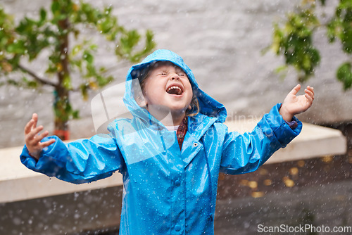 Image of Winter, rain coat and a girl playing in the weather outdoor alone, having fun during the cold season. Children, water or wet with an adorable small female kid standing arms outstretched outside