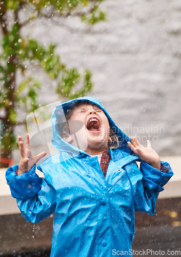 Image of Wet weather, raincoat and a girl playing in the rain outdoor alone, having fun during the cold season. Kids, winter or freedom with an adorable little female child standing arms outstretched outside