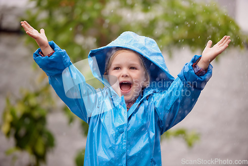Image of Winter, raincoat and a happy girl playing in the rain outdoor alone, having fun during the cold season. Kids, water or wet with an adorable little female child standing arms outstretched outside