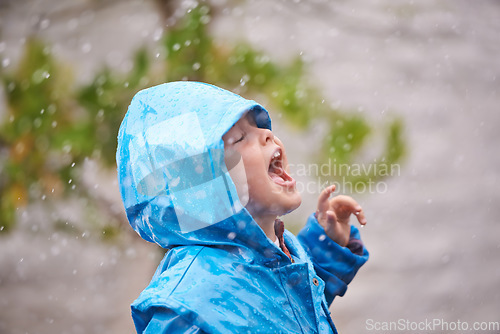 Image of Winter, raincoat and a girl having fun in the rain outdoor alone, playing during the cold season. Kids, water or wet weather with an adorable little female child standing arms outstretched outside