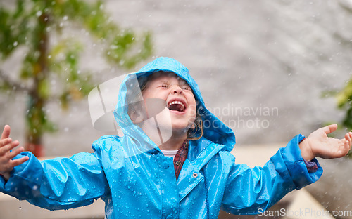 Image of Winter, rain jacket and a girl playing in the weather outdoor alone, having fun during the cold season. Children, water or wet with an adorable little female kid standing arms outstretched outside