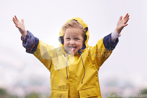 Image of Winter, raincoat and a girl playing in the water outdoor alone, having fun during the cold season. Kids, rain or wet with an adorable little female child standing arms outstretched outside in the day