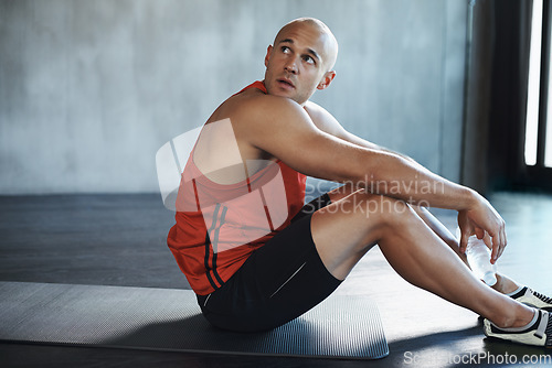 Image of Workout, looking and man relax on floor after health club exercise, sports commitment or gym training. Tired breathing, thinking man and healthy person sitting after cardio, fitness or challenge