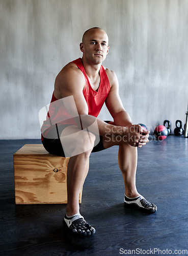 Image of Exercise, serious and portrait of man sitting after bodybuilding workout, sports performance or gym studio commitment. Active, bodybuilder focus and healthy person with fitness progress determination