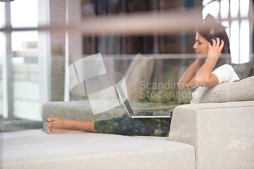 Image of Woman, headphones and a laptop for internet on a home sofa while listening to music or streaming audio. Female student relax on couch to listen to radio channel, podcast or learn language online