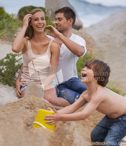 Image of Family, laughing and sand castle at beach in summer for fun, travel or holiday with love. A man, woman and excited kid playing together on vacation at sea with a toy bucket, development and happiness