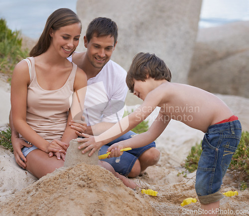 Image of Family, child and building sand castle at beach in summer for fun, travel or holiday with love. A man, woman and kid playing together on vacation at sea with a toy bucket, development and happiness