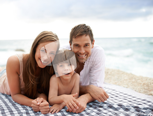 Image of Beach, family and portrait outdoor in summer on a picnic blanket for travel vacation to relax. Smile of a man, woman and child or son happy together on holiday at sea with love, care and happiness