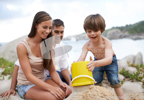 Image of Family, child and sand castle at beach in summer for fun, travel or holiday with a smile. A man, woman and excited kid playing together on vacation at sea with a toy bucket, development and happiness
