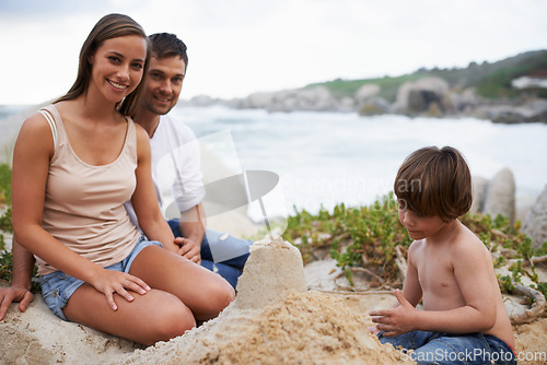 Image of Family, child and sand castle portrait at beach in summer for fun, travel or holiday. A man, woman and kid playing together on vacation at sea for quality time, development and happiness outdoor