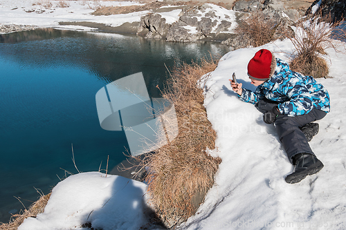 Image of Young boy taking photos on the coast river